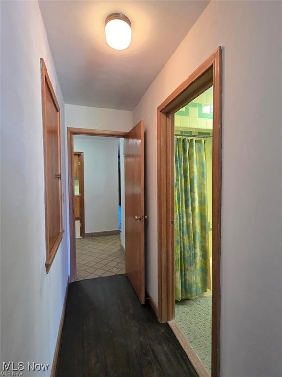 hall with baseboards and wood finished floors