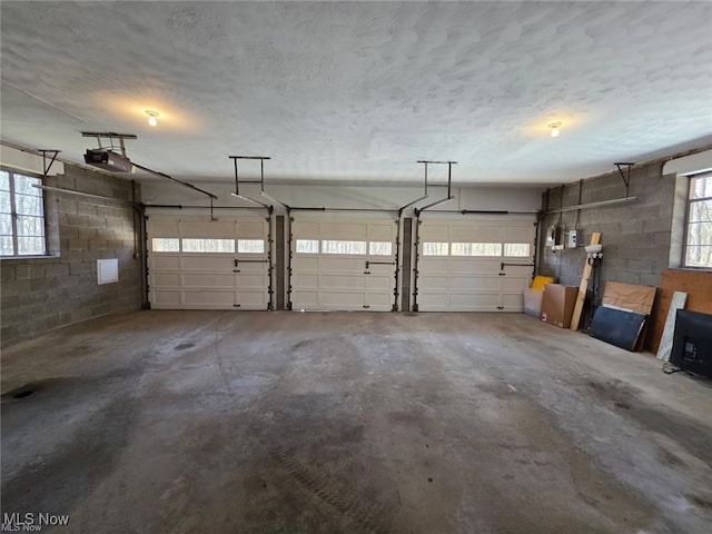 garage with a garage door opener and concrete block wall
