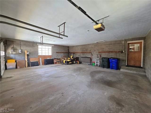 garage with a garage door opener and concrete block wall