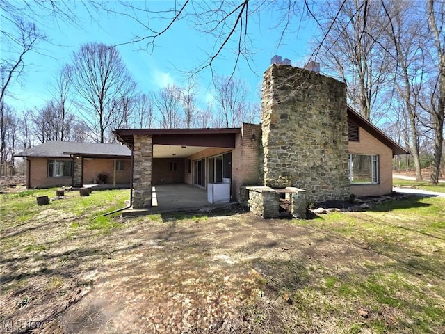 back of house featuring a patio area, brick siding, and an attached carport