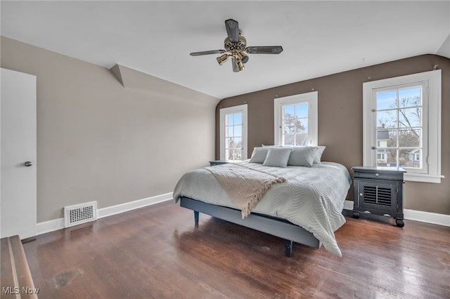 bedroom with visible vents, multiple windows, vaulted ceiling, and wood finished floors