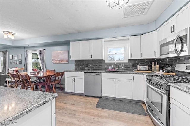 4000 S Mahoning Ave, Alliance, OH 44601 - kitchen featuring visible vents, a sink, light wood-type flooring, stainless steel appliances, and decorative backsplash
