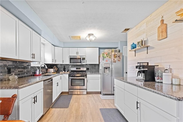 4000 S Mahoning Ave, Alliance, OH 44601 - kitchen with tasteful backsplash, white cabinets, appliances with stainless steel finishes, a sink, and light wood finished floors