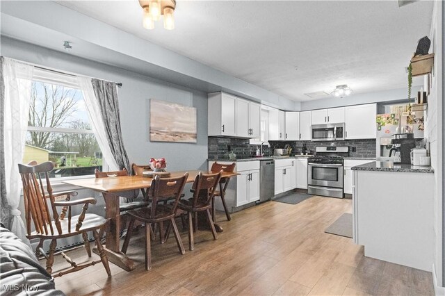 4000 S Mahoning Ave, Alliance, OH 44601 - kitchen with tasteful backsplash, light wood-type flooring, dark countertops, white cabinets, and appliances with stainless steel finishes