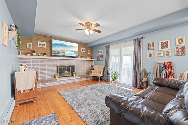4000 S Mahoning Ave, Alliance, OH 44601 - living room with a baseboard heating unit, a brick fireplace, wood walls, ceiling fan, and wood-type flooring