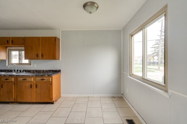 kitchen featuring visible vents, brown cabinets, a sink, and dark countertops
