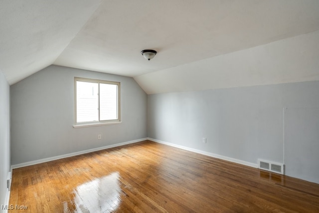 bonus room with visible vents, baseboards, vaulted ceiling, and wood finished floors