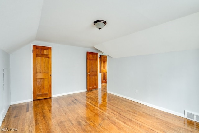 additional living space featuring visible vents, baseboards, light wood finished floors, and lofted ceiling
