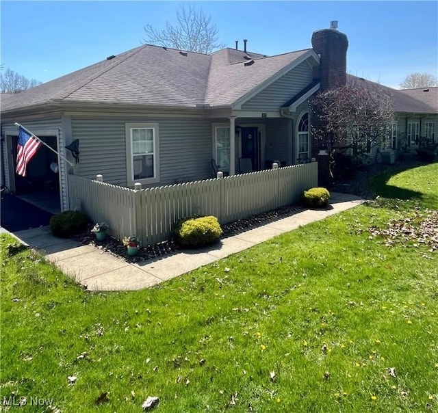 47 Woodland Chase Blvd, Niles, OH 44446 - rear view of property with a chimney, a shingled roof, a lawn, and a fenced front yard
