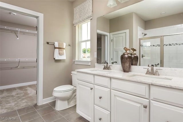 bathroom with a shower stall, double vanity, a sink, and toilet