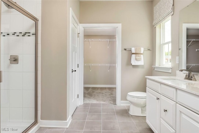 bathroom featuring a shower stall, vanity, toilet, tile patterned floors, and baseboards