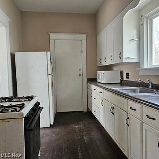 702 Dickson St, Youngstown, OH 44502 - kitchen featuring white cabinets, a sink, dark countertops, white appliances, and dark wood-style floors