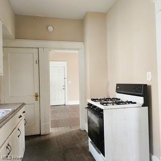 702 Dickson St, Youngstown, OH 44502 - kitchen with white gas stove, dark wood-style flooring, white cabinets, and baseboards