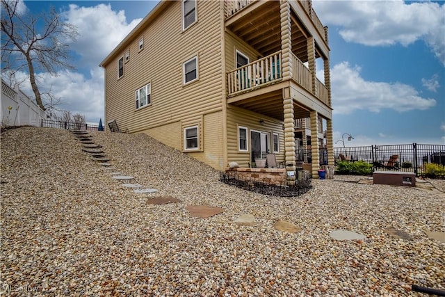 back of property featuring a patio area, a balcony, and fence