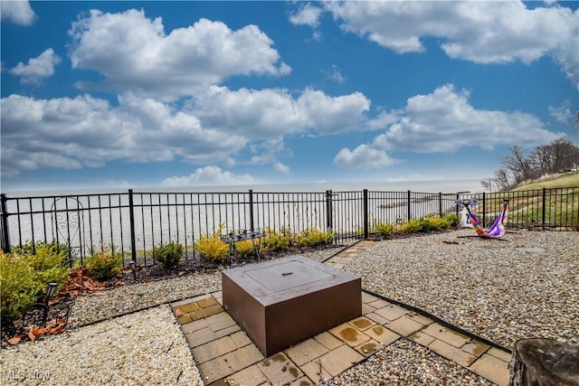 view of patio / terrace featuring fence and a water view