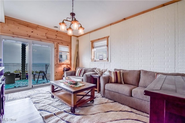 living room featuring a chandelier, crown molding, wood finished floors, and wooden walls