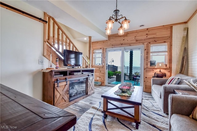 living area with a chandelier, light wood-type flooring, wood walls, and a wealth of natural light