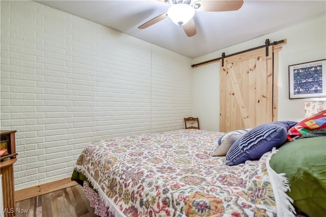 bedroom featuring a barn door, a ceiling fan, and wood finished floors
