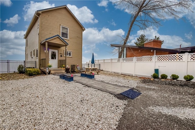 rear view of property featuring a patio area, a fenced backyard, and log veneer siding