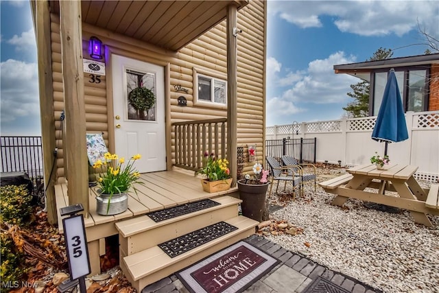 property entrance with fence and faux log siding