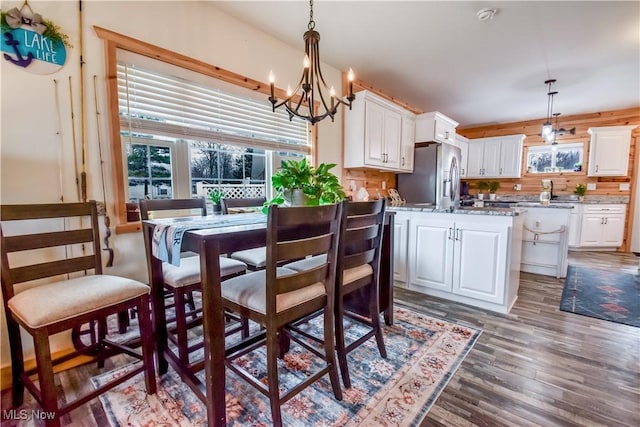 dining space with wood finished floors, an inviting chandelier, and plenty of natural light
