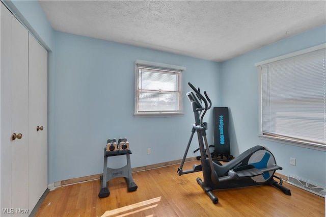 1863 Beaver Trl, Mineral Ridge, OH 44440 - workout room with a textured ceiling, wood finished floors, baseboards, and visible vents