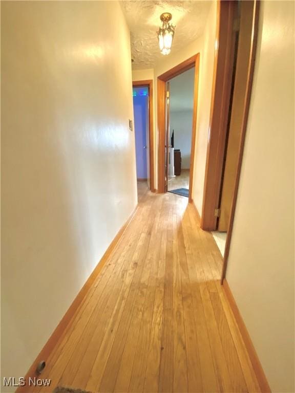 hall with light wood-style floors and baseboards