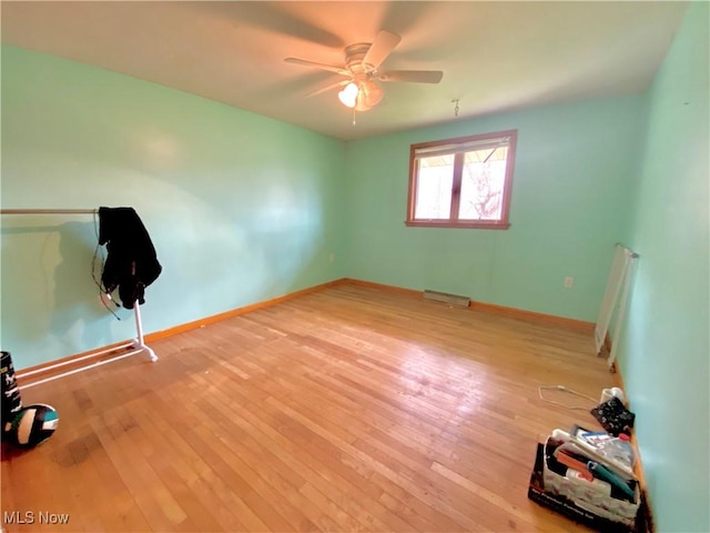 spare room with hardwood / wood-style floors, baseboards, a ceiling fan, and visible vents