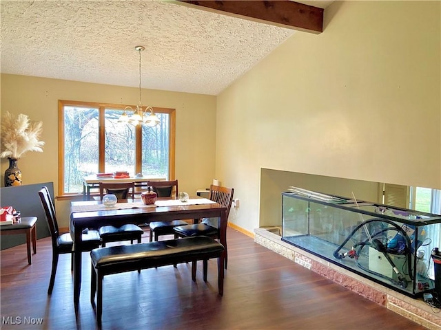 dining space featuring dark wood-type flooring, a textured ceiling, an inviting chandelier, and lofted ceiling