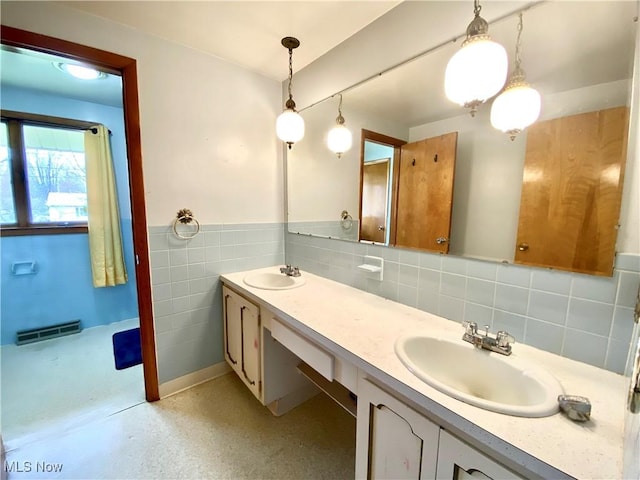 full bathroom featuring double vanity, visible vents, a sink, and wainscoting