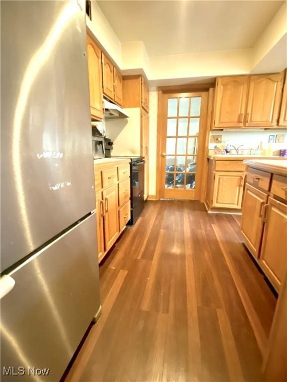 kitchen featuring dark wood-style flooring, light countertops, freestanding refrigerator, under cabinet range hood, and black range with electric cooktop