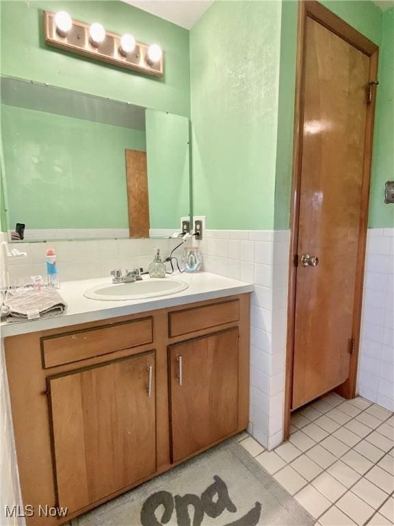 bathroom featuring tile patterned flooring, vanity, wainscoting, and tile walls