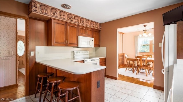 165 Reservoir Rd, New Concord, OH 43762 - kitchen featuring white appliances, a kitchen breakfast bar, brown cabinets, light countertops, and wallpapered walls
