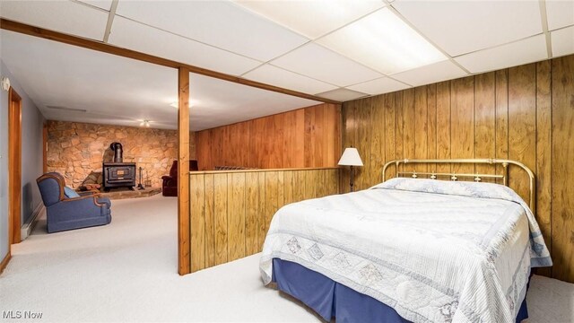 165 Reservoir Rd, New Concord, OH 43762 - carpeted bedroom with wood walls, a wood stove, and a drop ceiling