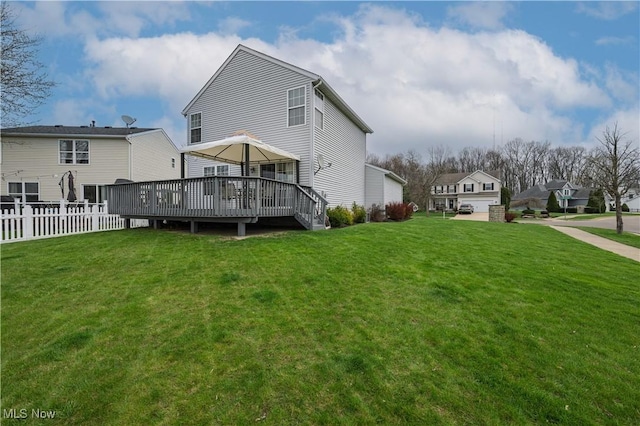 rear view of property with a yard, a wooden deck, and fence