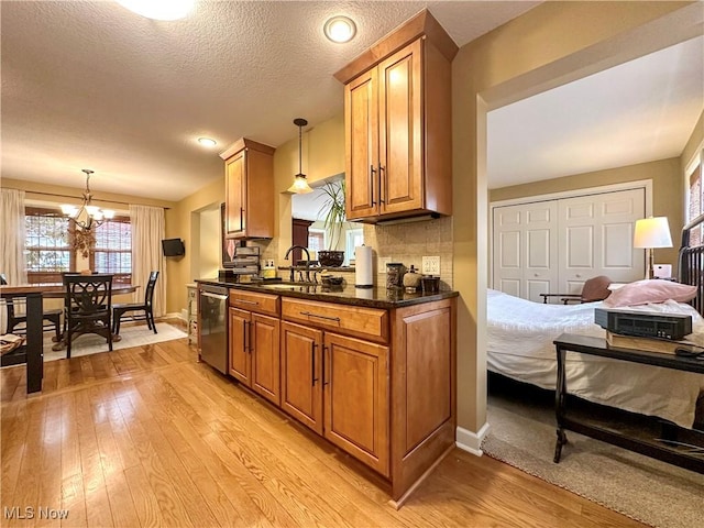 835 John St, Niles, OH 44446 - kitchen featuring a sink, brown cabinetry, dishwasher, light wood-style flooring, and a notable chandelier
