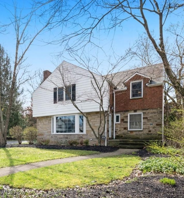 4090 Silsby Rd, University Heights, OH 44118 - view of front of home featuring a chimney, stone siding, and a front lawn