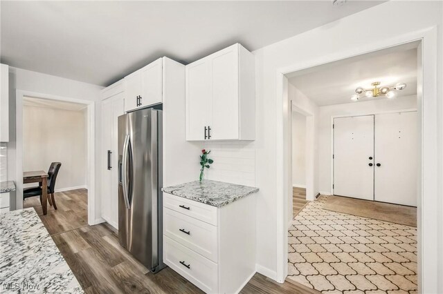 kitchen with dark wood finished floors, white cabinetry, light stone counters, and stainless steel fridge