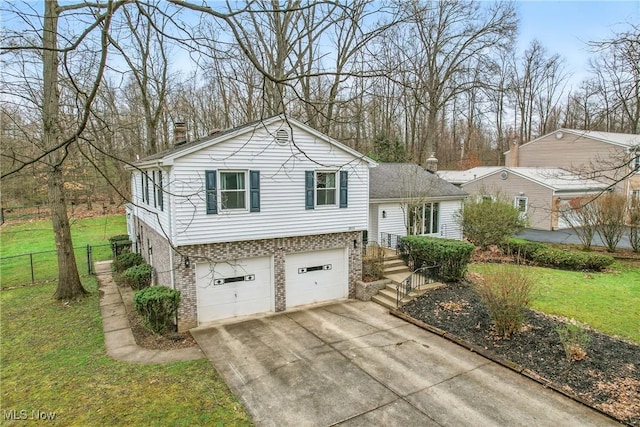 tri-level home featuring concrete driveway, a garage, fence, and a front lawn