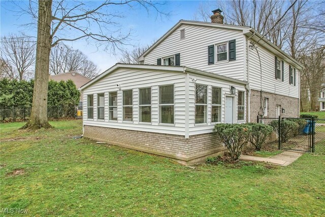 view of home's exterior with a lawn, a gate, fence, brick siding, and a chimney