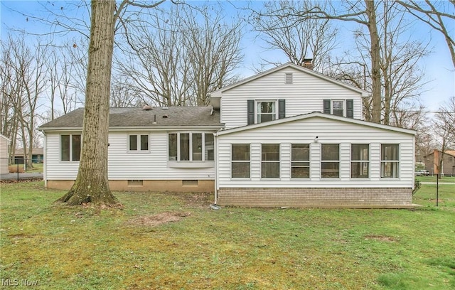 back of property with roof with shingles, crawl space, a chimney, and a lawn