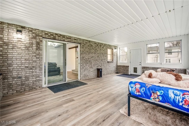 bedroom featuring brick wall and wood finished floors