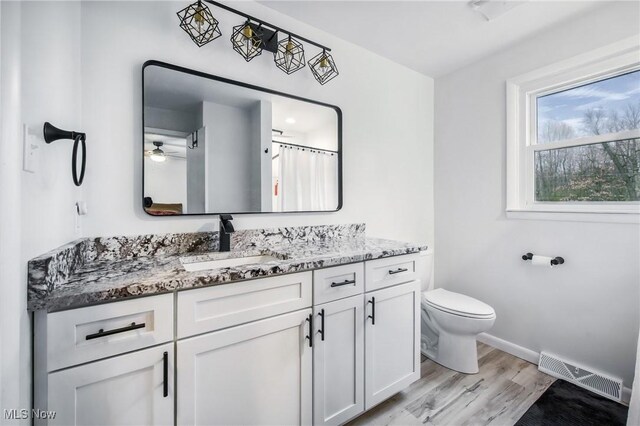 bathroom featuring vanity, baseboards, toilet, visible vents, and wood finished floors