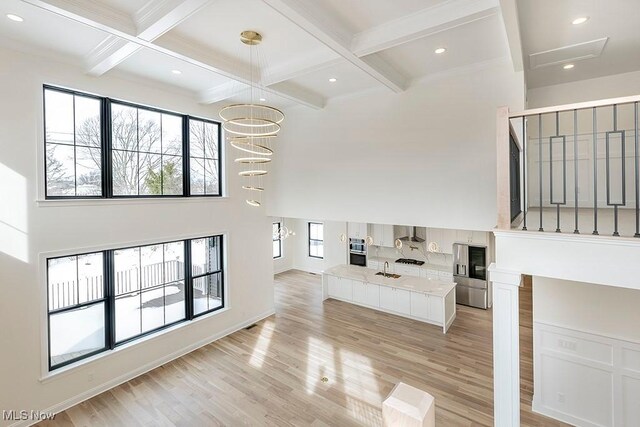 2762 Rocky Ridge Dr, Westlake, OH 44145 - unfurnished living room featuring a towering ceiling, recessed lighting, light wood-style flooring, beamed ceiling, and coffered ceiling