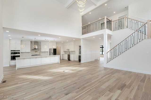 2762 Rocky Ridge Dr, Westlake, OH 44145 - unfurnished living room with a high ceiling, decorative columns, recessed lighting, light wood finished floors, and stairway