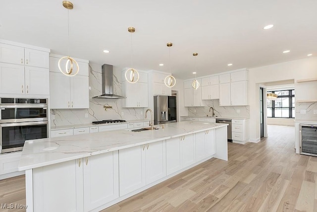 2762 Rocky Ridge Dr, Westlake, OH 44145 - kitchen featuring wall chimney exhaust hood, white cabinetry, appliances with stainless steel finishes, a sink, and beverage cooler
