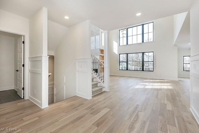 2762 Rocky Ridge Dr, Westlake, OH 44145 - unfurnished living room with baseboards, recessed lighting, stairway, light wood-style floors, and decorative columns