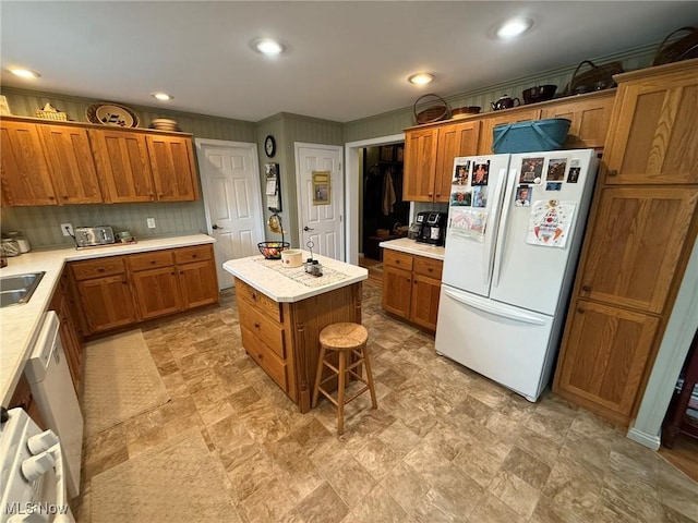 kitchen with brown cabinets, freestanding refrigerator, light countertops, and a kitchen island