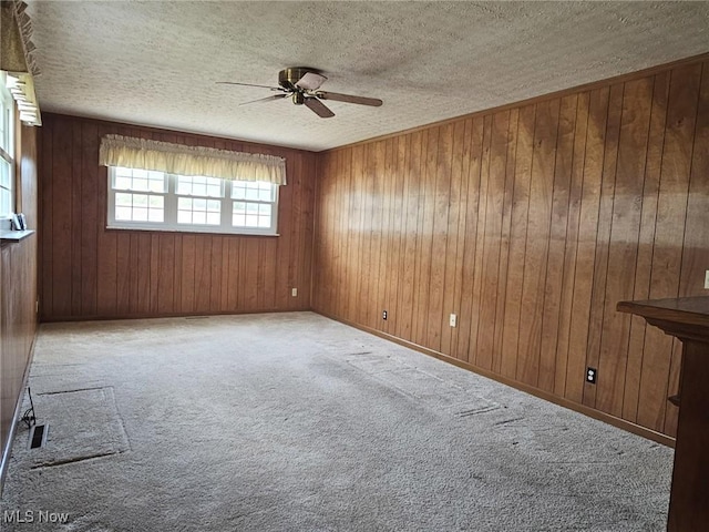 3509 11th Ave, Vienna, WV 26105 - spare room with a textured ceiling, wood walls, carpet flooring, and a ceiling fan