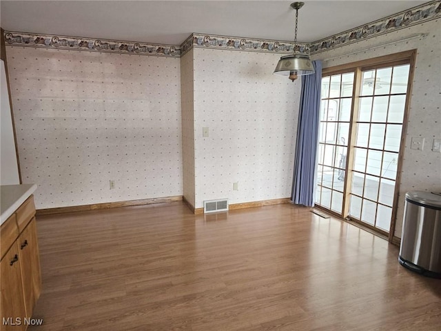 3509 11th Ave, Vienna, WV 26105 - unfurnished dining area featuring wallpapered walls, wood finished floors, baseboards, and visible vents